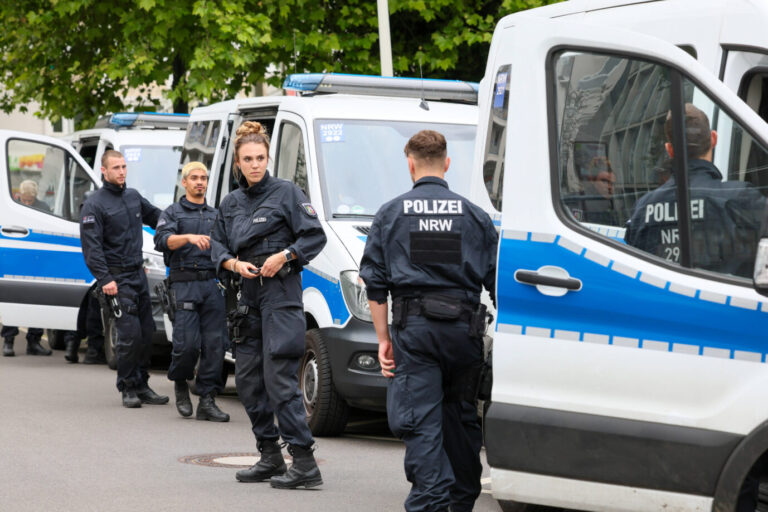Auf einer Straße stehen mehrere Polizisten in Uniformen - Symbolbild dafür, daß Migranten in Aachen vermutlich einen angeblichen rassistischen Anschlag vorgetäuscht haben