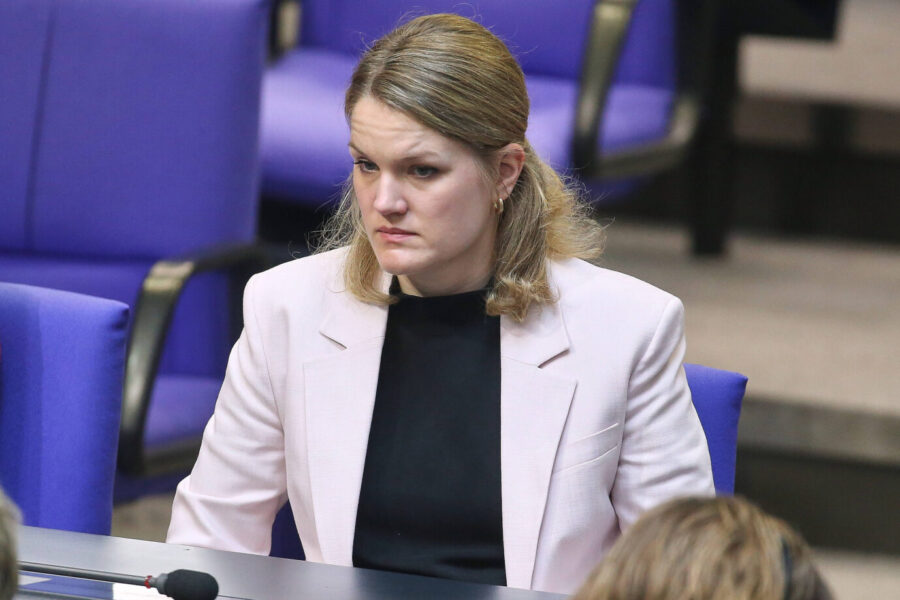 Sonja Eichwede, SPD-Bundestagsabgeordnete, sitzt mit ernstem Gesichtsausdruck an einem Tisch im Plenarsaal des Bundestags. Sie trägt einen hellen Blazer über einem schwarzen Oberteil. Im Hintergrund sind lila Polsterstühle erkennbar.