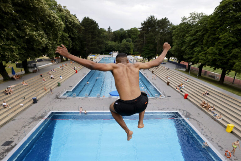 Ein junger Mann springt mit ausgebreiteten Armen von einem Sprungturm ins Becken des Kölner Stadionbads. Im Hintergrund sind mehrere Badegäste auf den Tribünen und in den Schwimmbecken zu sehen. Die Aufnahme entstand am 25. Juni 2025 bei schwülem Sommerwetter in Köln. Die Szene steht im Kontrast zur politischen Debatte um Übergriffe in Freibädern, über die die AfD anhand neuer Zahlen des Innenministeriums diskutiert. Ein junger Mann springt vom Freibadturm: Ausländer stellen die Mehrheit der Tatverdächtigen bei Sexualdelikten. Foto: IMAGO / Panama Pictures