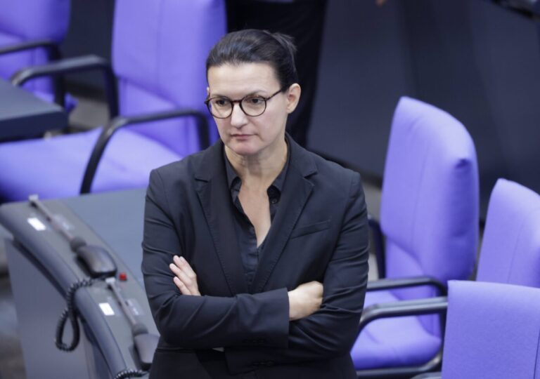 Irene Mihalic, Parlamentarische Geschäftsführerin der Grünen-Fraktion im Bundestag, steht mit verschränkten Armen in schwarzem Blazer zwischen lila Stühlen im Plenarsaal. Sie wirkt ernst und konzentriert. Irene Mihalic (Grüne) im Bundestag: Sie zweifelt an der Notlage-Begründung für die Grenzkontrollen