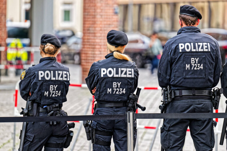 Auf einer Straße stehen mehrere Polizisten in Uniformen - Symbolbild dafür, daß Migranten in Aachen vermutlich einen angeblichen rassistischen Anschlag vorgetäuscht haben