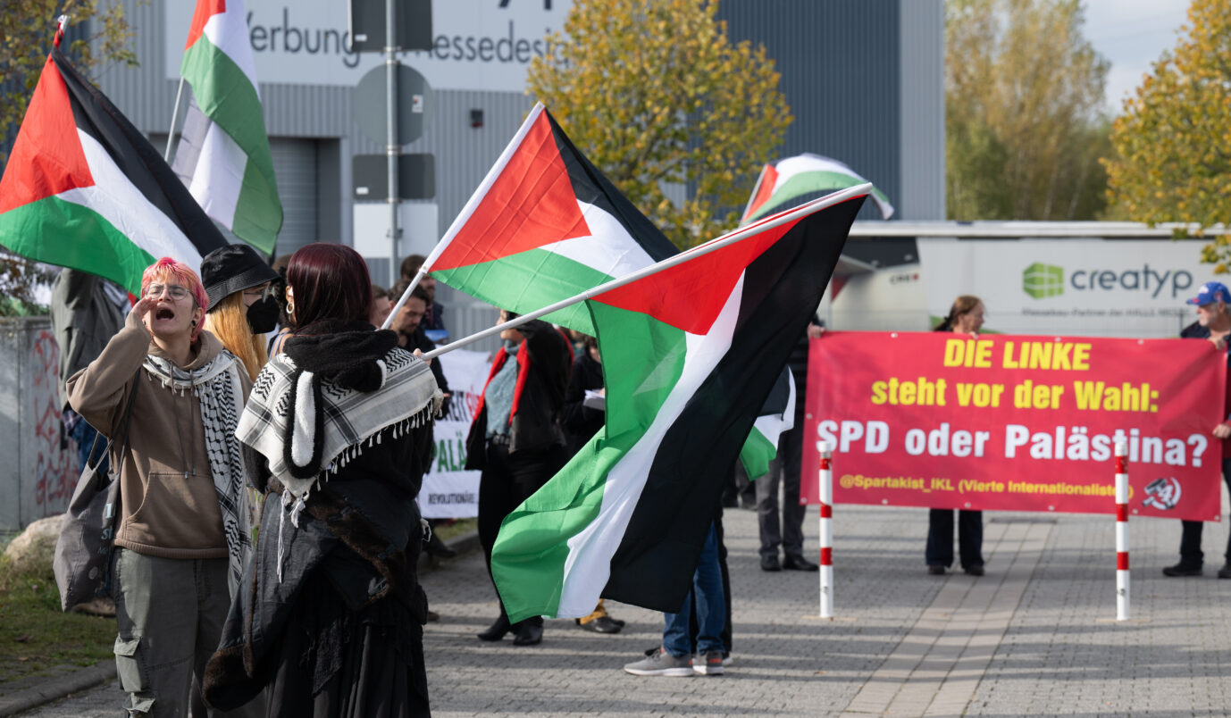 Palästina-Flaggen wehen auf einer propalästinensischen Kundgebung auf dem Messegelände, wo der Bundesparteitag der Partei Die Linke stattfindet. Auf einem Transparent steht «Die Linke steht vor der Wahl: SPD oder Palästina?»