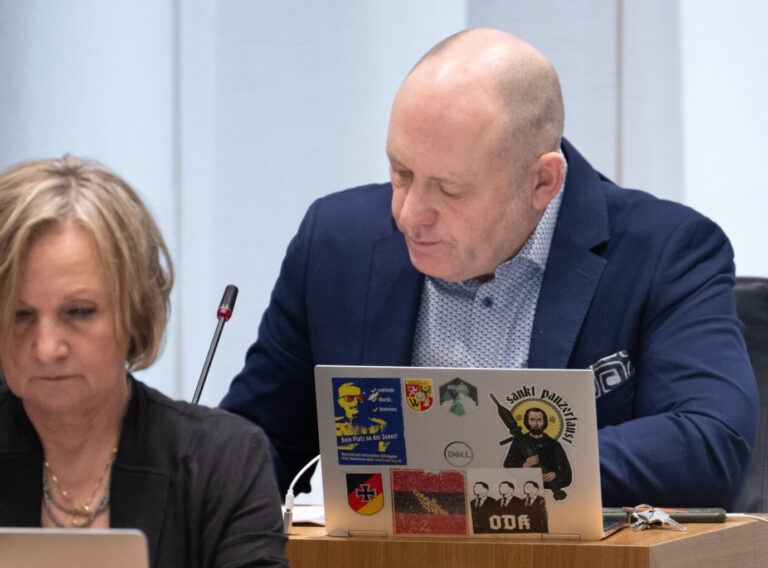 Ein Mann mit Glatze sitzt im Parlament von Rheinland-Pfalz vor einem Laptop mit auffälligen Aufklebern, daneben eine Frau mit blondem Haar. Beide blicken konzentriert nach unten. AfD-Politiker Joachim Paul im Landtag von Rheinland-Pfalz: Als Oberbürgermeisterkandidat ausgeschlossen – und möglicherweise nicht der letzte. Foto: picture alliance/dpa | Boris Roessler