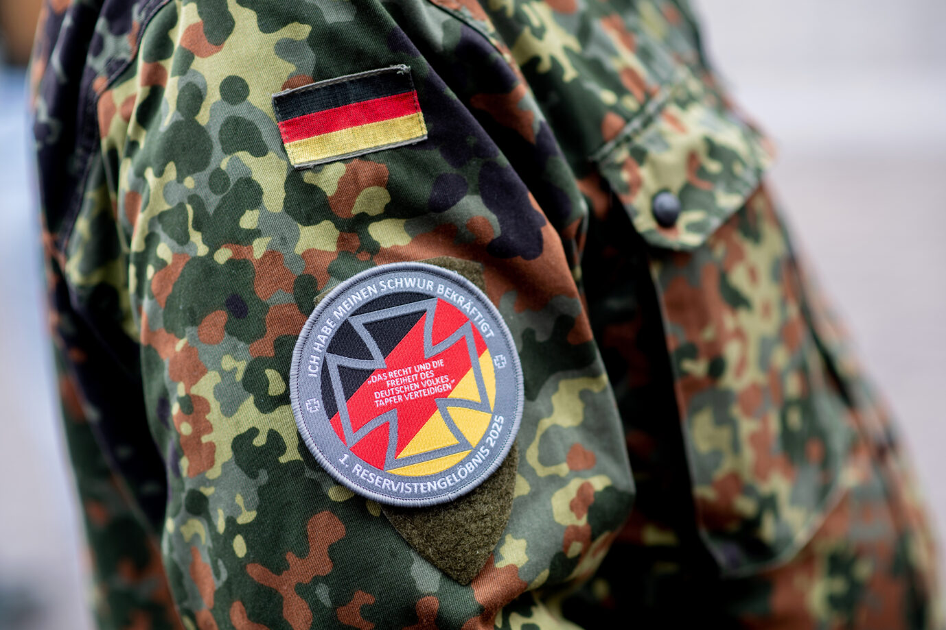 Ein Reservist der Bundeswehr trägt im Rahmen eines Reservistenappells zum Nationalen Veteranentag ein Abzeichen mit der Aufschrift „Ich habe meinen Schwur bekräftigt“ und dem Zusatz „1. Reservistengelöbnis 2025“ auf seiner Uniform. Symbolbild: picture alliance/dpa | Hauke-Christian Dittrich