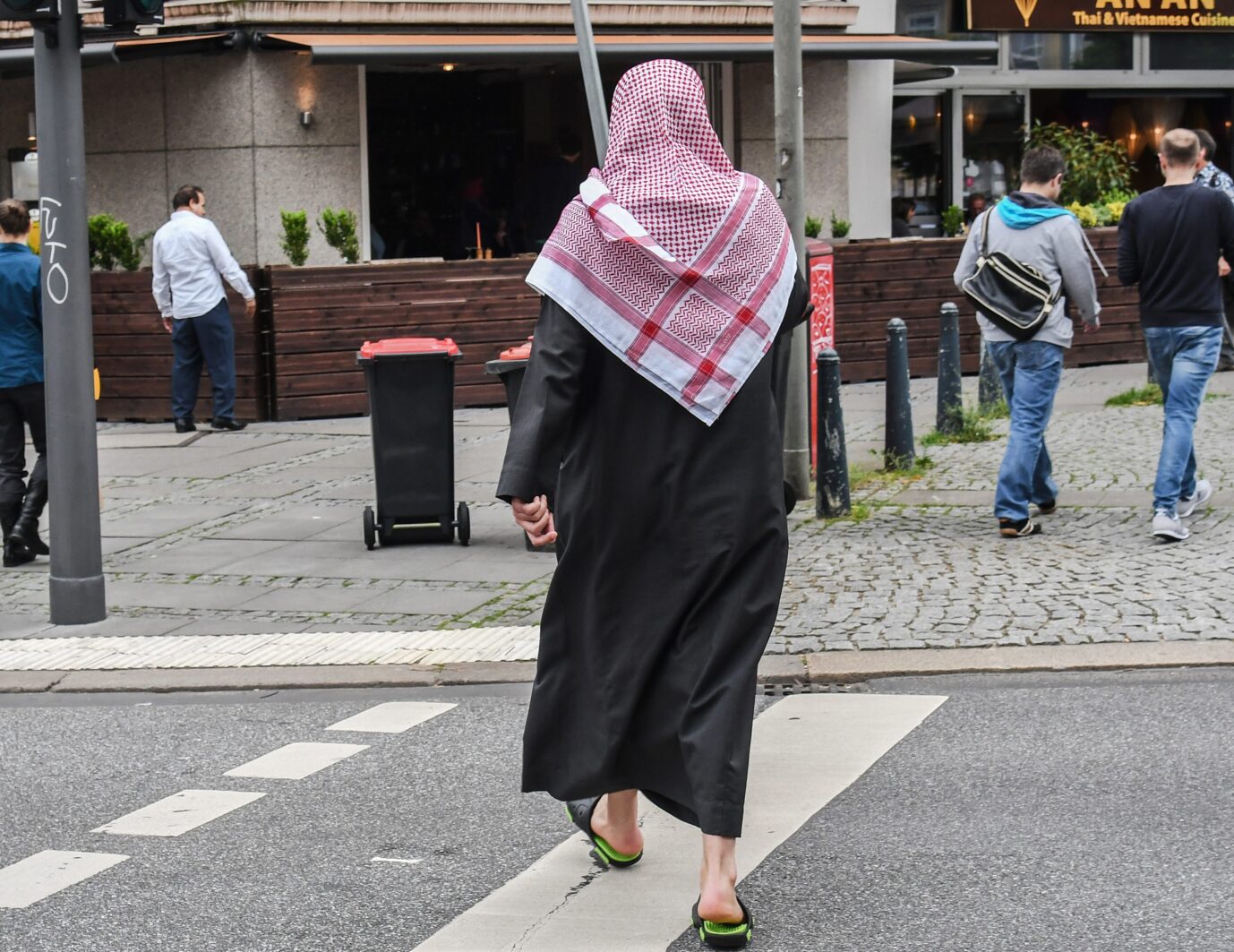 Ein Mann mit rot-weißem Kopftuch und langem schwarzem Gewand überquert in Hamburg nahe dem Hauptbahnhof eine Straße. Die Hamburger Innenstadt: Sozialausgaben Afghanen in der Hansestadt steigen jährlich. Foto: picture alliance / Winfried Rothermel | Winfried Rothermel