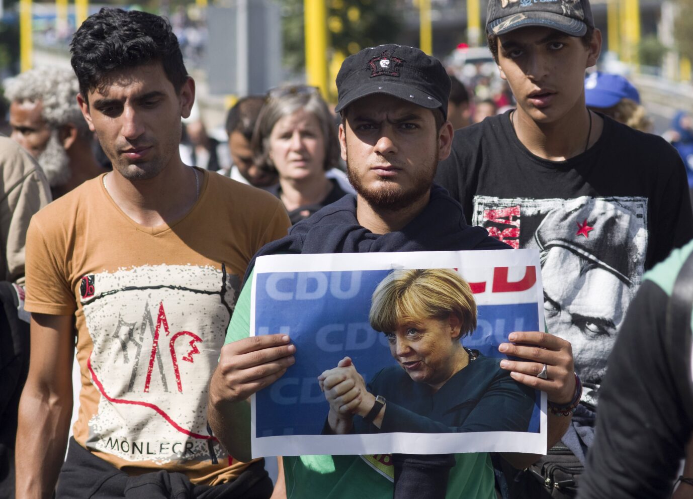 Asylmigranten halten ein Bild von Merkel in die Kamera. Sie wollen den deutschen Paß.