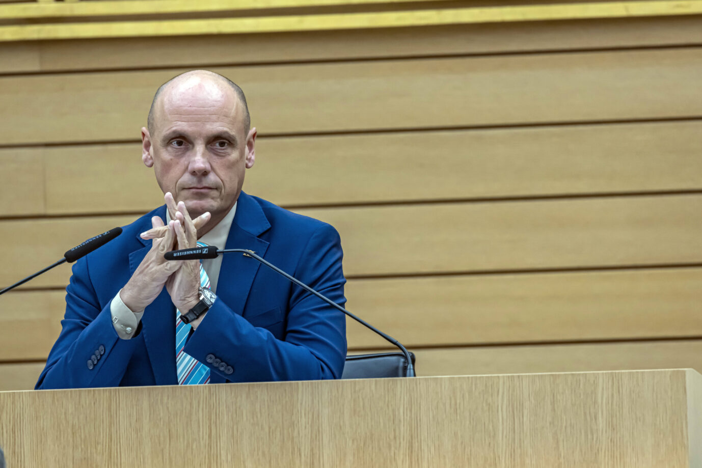 Ein Mann in blauem Anzug und gestreifter Krawatte sitzt an einem Rednerpult mit zwei Mikrofonen in einem Plenarsaal und hat die Hände vor sich verschränkt. Hakenkreuzkritzler Daniel Born in seiner Rolle als Landtagsvizepräsident von Baden-Württemberg: keine Ermittlungen gegen den Sozialdemokraten. Foto: IMAGO / Arnulf Hettrich