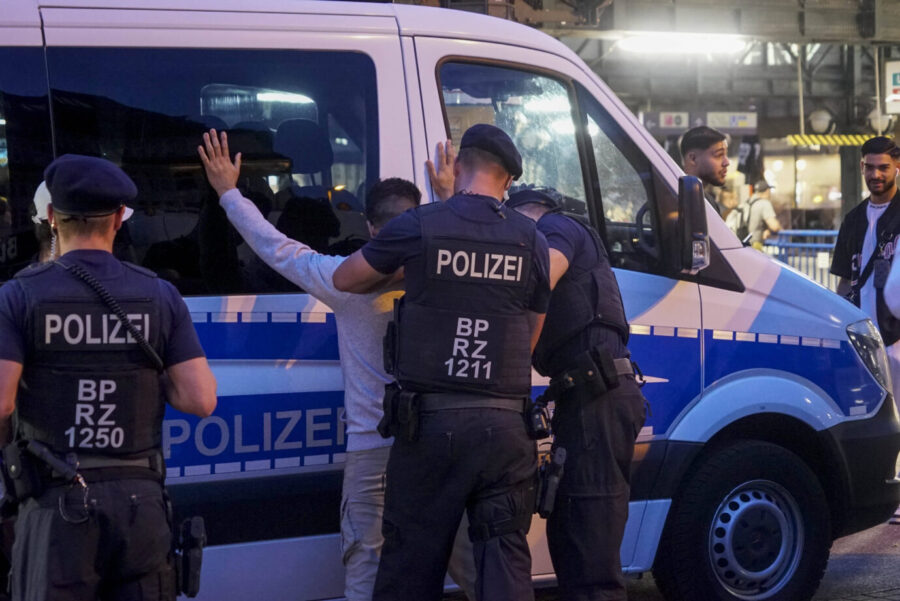 Mehrere Bundespolizisten kontrollieren am Hamburger Hauptbahnhof einen Mann vor einem Polizeifahrzeug während einer temporären Waffenverbotszone. Die Beamten durchsuchen ihn, im Hintergrund beobachten Passanten. Kontrolle am Hamburger Hauptbahnhof: Die Bundespolizei registriert mehr Messerdelikte bundesweit. Foto: IMAGO / BREUEL-BILD