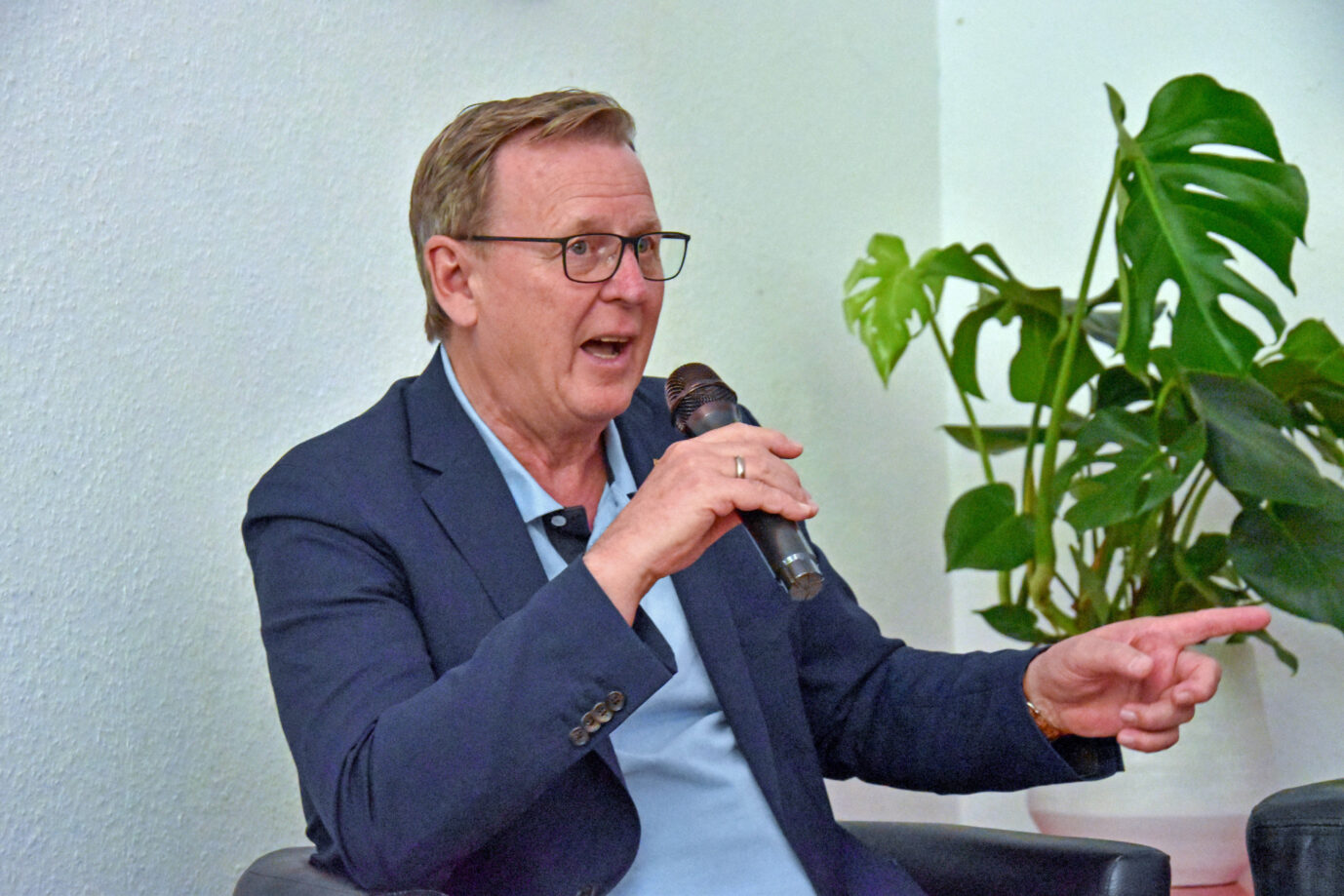 Bundestagsvizepräsident und Thüringens Ministerpräsident Bodo Ramelow (Linke) sitzt auf einem Stuhl, gestikuliert mit einer Hand und schaut grantig – wahrscheinlich, weil Merkel jetzt nicht mehr Kanzlerin ist und deswegen minimal weniger Einwanderer kommen