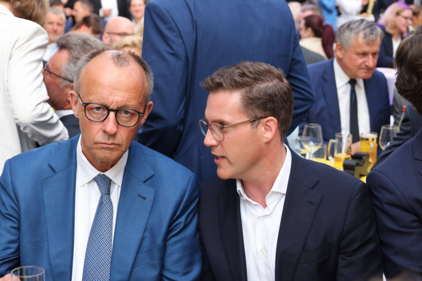 Friedrich Merz und Manuel Hagel bei einer Veranstaltung in der baden-württembergischen Landesvertretung in Berlin am 10. Juli 2025. Merz blickt ernst in die Kamera, trägt Brille, weißes Hemd und blauen Anzug. Rechts neben ihm spricht Hagel mit Brille, weißem Hemd und dunklem Sakko. Im Hintergrund sitzen zahlreiche Gäste an gedeckten Tischen mit Wein- und Biergläsern. Die Szene wirkt politisch konzentriert, aber informell. Merz und Hagel beim Stallwächterempfang: Kurz darauf distanzierte sich der CDU-Landeschef vom Kurs des Kanzlers. Foto: IMAGO / Frank Ossenbrink
