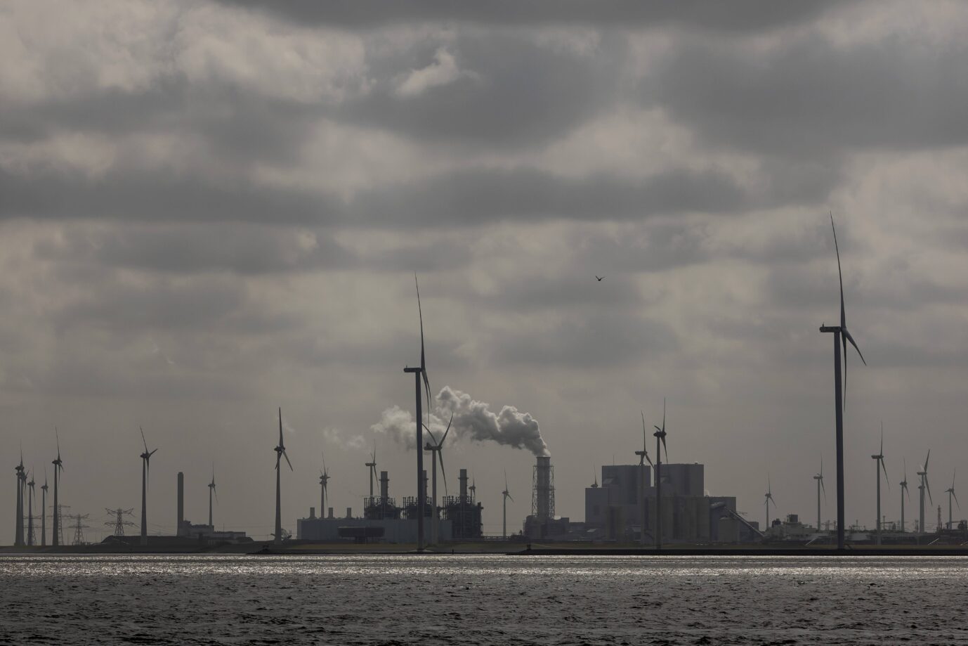 Unter einem grauen bewölkten Himmel sind Windräder und rauchende Schornsteine zu sehen – es handelt sich um eine Kohle- und Windenergieanlage im niederländischen Eemshaven – Symbolbild dafür, daß CO2 wohl gar kein so krasser Klimakiller ist, wie gedacht