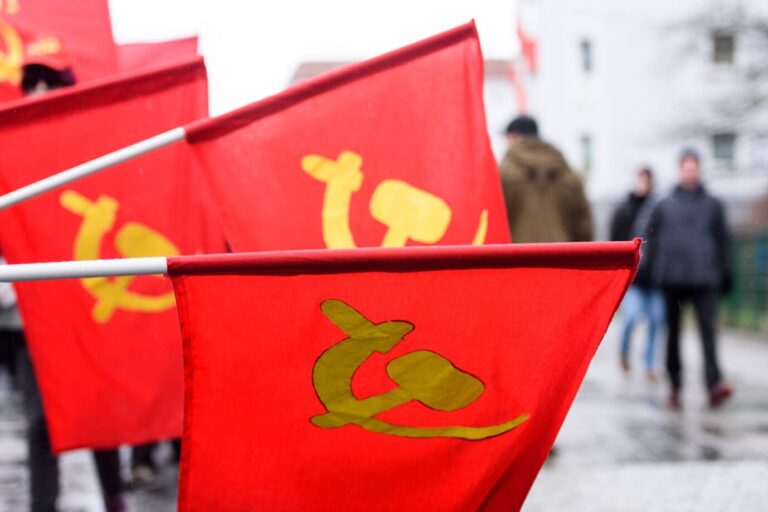 Auf roten Fahnen sind Hammer und Sichel zu sehen – ähnlich wie auf dem Pullover der neuen Linken-Abgeordneten Lin Lindner