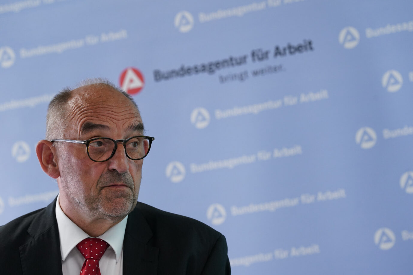 Ein älterer Mann mit Brille, Anzug und roter Krawatte sitzt vor einer blauen Wand mit dem Logo der Bundesagentur für Arbeit. Detlef Scheele, damaliger Vorstandschef der Bundesagentur für Arbeit, während einer Pressekonferenz zu den Arbeitsmarktdaten. Detlef Scheele: Der frühere Chef der Bundesagentur für Arbeit warnte vor Bürgergeld als Geschäftsmodell. Foto: picture alliance/dpa | Marcus Brandt