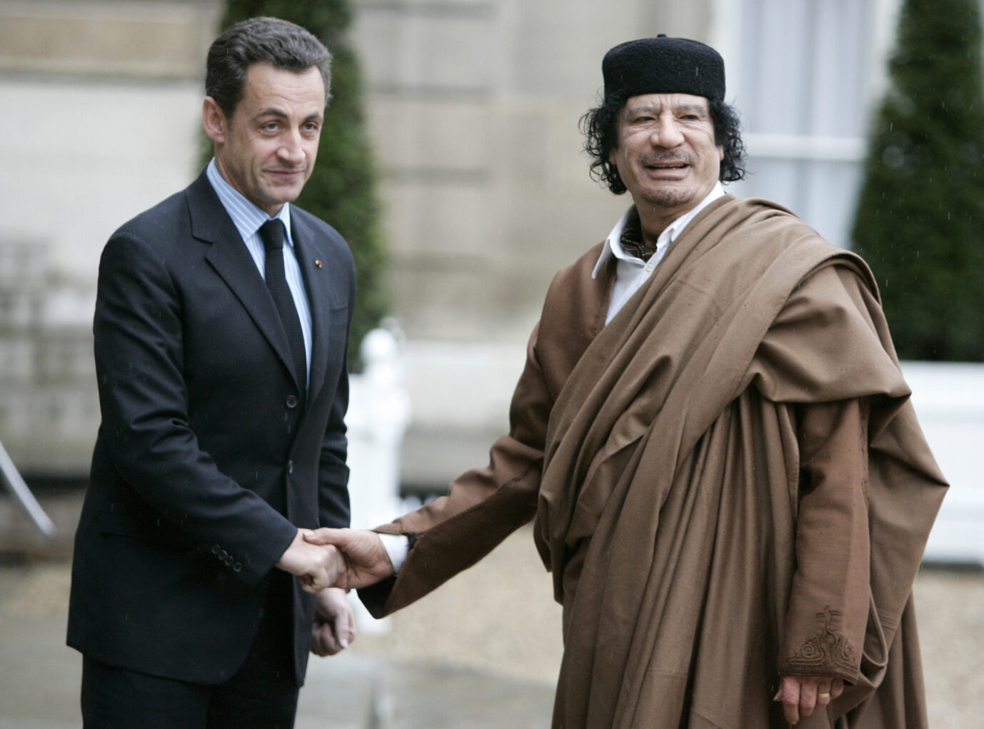 Links steht der ehemalige französische Präsident Nicolas Sarkozy und schüttelt die Hand des rechts stehenden damaligen libyschen Machthabers Muammar al-Gaddafi, von dem er sich wohl hat finanzieren lassen