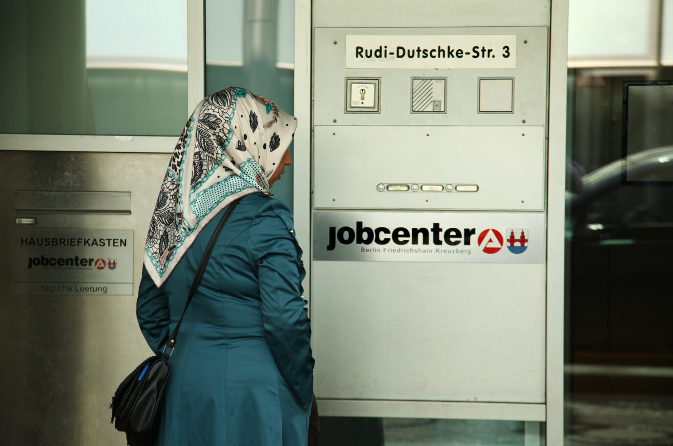 Eine Muslima mit Kopftuch steht vor einem Jobcenter in Berlin im Bezirk Kreuzberg am 13.09.2013. Der Arbeitsmarkt profitiert nicht von der aktuellen Migrationspolitik. Foto: Wolfram Steinberg dpa