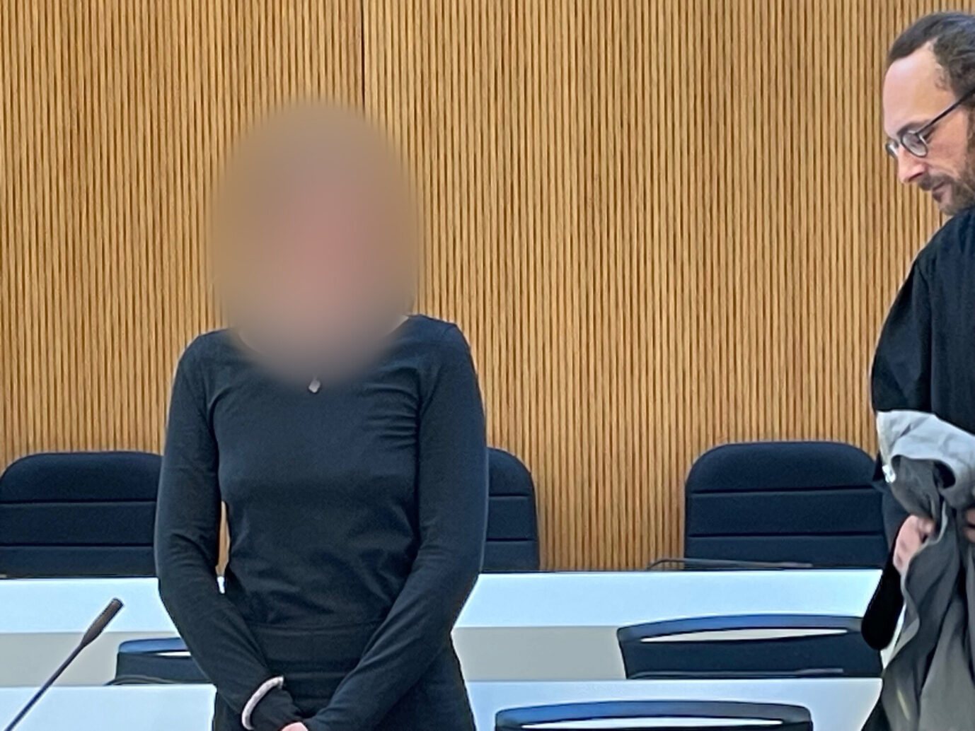Eine Frau in schwarzer Kleidung steht neben ihrem Verteidiger in einem Gerichtssaal, im Hintergrund sind Holzwände und leere Stühle zu sehen. Gezeigt wird die Angeklagte Hanna S., die am Oberlandesgericht München wegen Beteiligung an Angriffen auf Rechtsextreme in Budapest zu fünf Jahren Haft verurteilt wurde. Die Angeklagte Hanna S. mit ihrem Verteidiger im Gerichtssaal: Das Oberlandesgericht München verurteilte die Linksextremistin zu fünf Jahren Haft. Foto: picture alliance/dpa | Alf Meier
