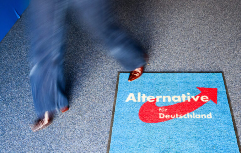 Eine Person mit rotem Schuh läuft über einen blauen Teppich mit dem Logo der AfD. Aufgenommen bei einer Wahlparty in der Bundesgeschäftsstelle der AfD vor der vorgezogenen Bundestagswahl 2025. Frau läuft über AfD-Teppich in der Bundesgeschäftsstelle: Die Partei muß Zentrale 2026 räumen. Foto: picture alliance/dpa | Julian Stratenschulte
