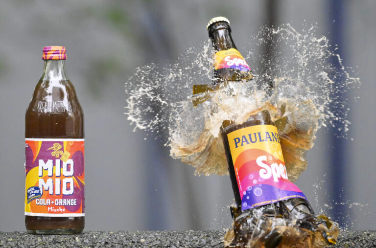 Links ist eine Spezi-Flasche der Marke Mio Mio und rechts eine zerspringende Spezi-Flasche von Paulaner