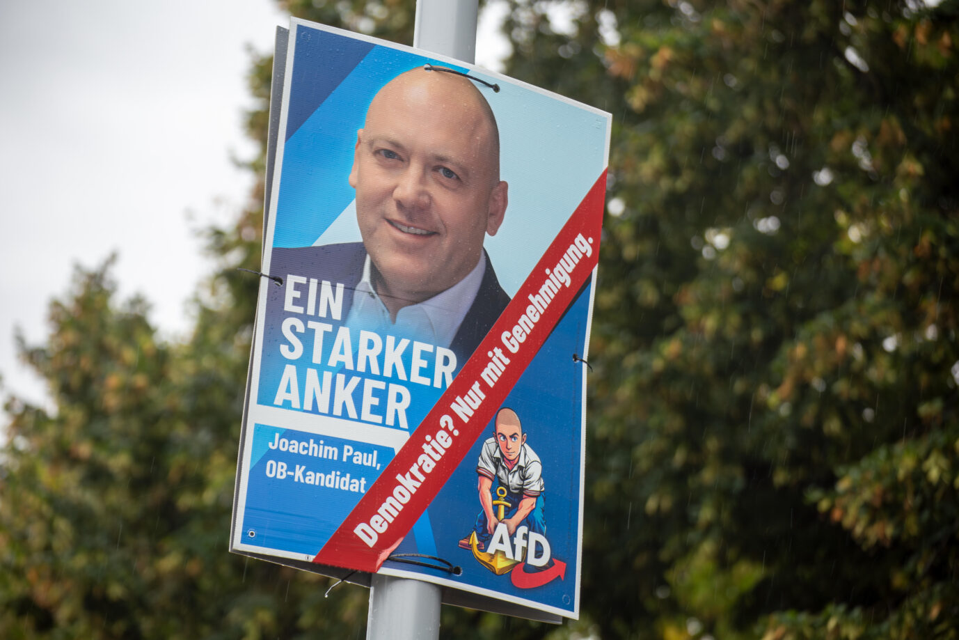 Wahlplakat des AfD-Politikers Joachim Paul in Ludwigshafen zur Oberbürgermeisterwahl. Auf dem Plakat ist ein Aufkleber mit der Aufschrift „Demokratie? Nur mit Genehmigung“ angebracht. Der Wahlausschuß der Stadt hatte Pauls Kandidatur abgelehnt. Wahlplakat von Joachim Paul in Ludwigshafen: Ein Aufkleber kommentiert die verweigerte Kandidatur. Foto: picture alliance / CHROMORANGE | Udo Herrmann