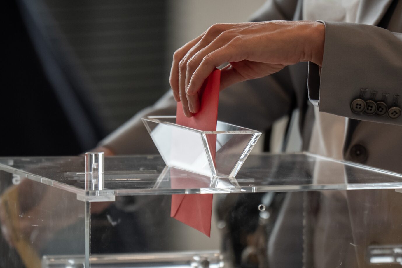 Eine Hand wirft einen roten Stimmzettel in eine durchsichtige Wahlurne im Bundestag. – Abgeordnete stimmen am 25. September 2025 geheim über die Besetzung von drei Posten am Bundesverfassungsgericht ab. Abgeordnete geben ihre Stimmzettel ab: Der Bundestag entscheidet in geheimer Wahl über drei neue Richter am Bundesverfassungsgericht. Foto: picture alliance/dpa | Michael Kappeler