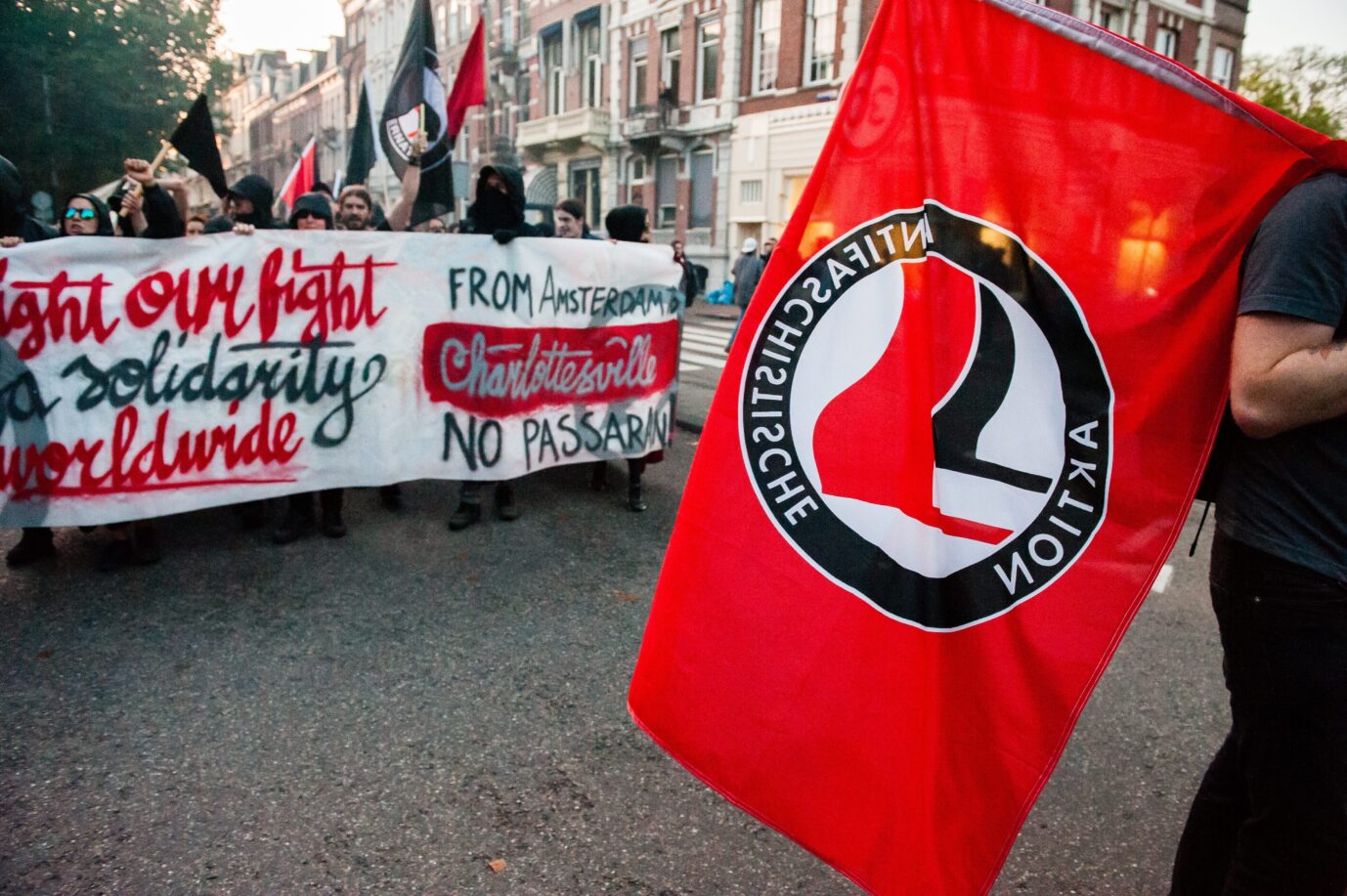 Demonstranten mit Transparenten und Antifa-Fahne bei einem Protestzug in Amsterdam im August 2017 gegen die Gewalt bei der rechten Kundgebung in Charlottesville (USA). Die Kundgebung führte auch am amerikanischen Konsulat vorbei. Antifa-Demonstration in Amsterdam 2017: Das niederländische Parlament will die Bewegung nun als Terrororganisation einstufen. Foto: picture alliance / NurPhoto | Romy Arroyo Fernandez