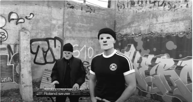 Zwei Männer mit weißen Masken und Adidas-artigen Tracksuits machen Musik: Das Popduo Deutsche Vita