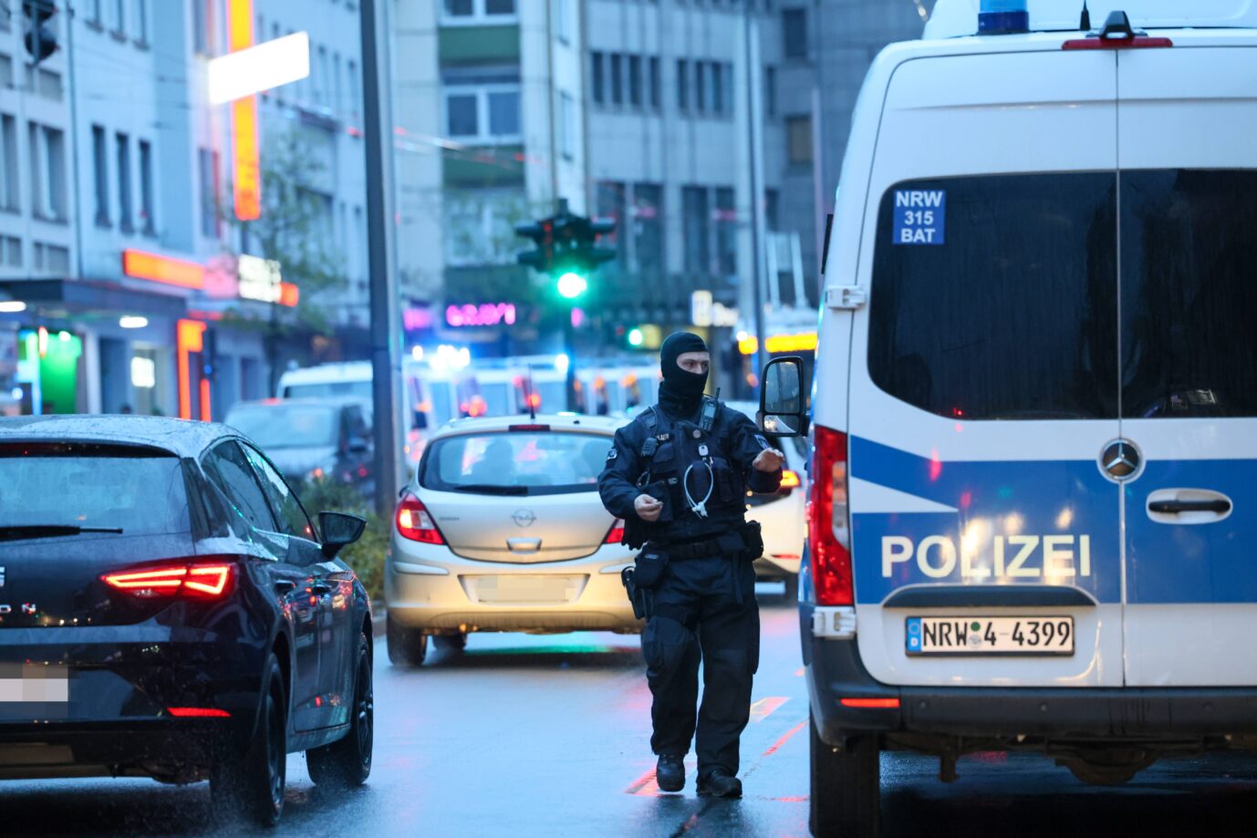 Ein maskierter Polizist steht neben einem Polizeitransporter – vielleicht macht er gerade eine Razzia gegen den Omeirat-Clan