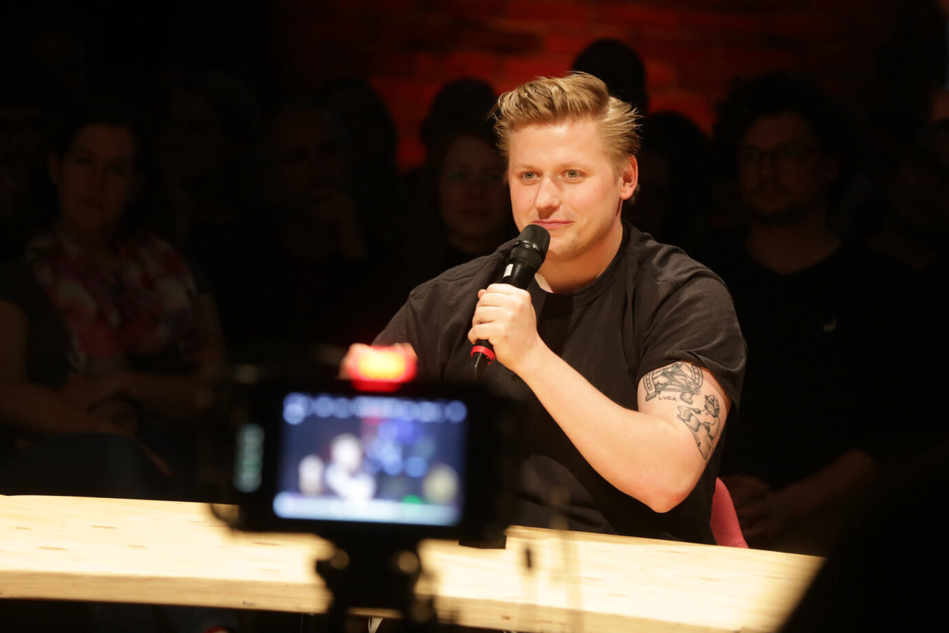 Sebastian Hotz, bekannt als El Hotzo, sitzt bei der Veranstaltung „PentagonTalk“ am 29. April 2024 im Dietrich-Keuning-Haus in Dortmund an einem runden Tisch, hält ein Mikrofon in der Hand und spricht ins Publikum. Darf wohl nicht mehr in die USA einreisen: Satiriker „El Hotzo“ bei einer Podiumsdiskussion. Foto: IMAGO / Cord