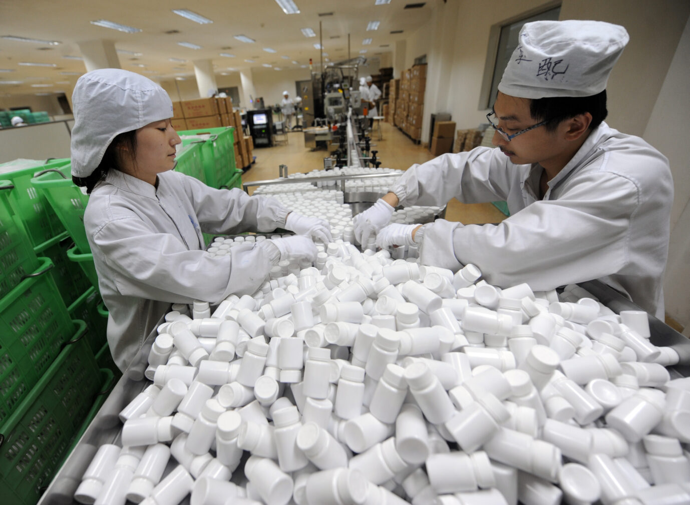 Zwei in weiß gekleidete chinesische Arbeiter in einer Pharmafabrik in China überprüfen die Verpackungen von Medikamenten