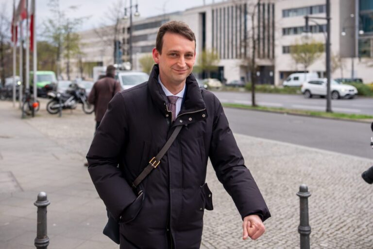 Der Leiter des Kanzlerbüros, Jacob Schrot (CDU), trägt eine schwarze Regenjacke und läuft eine Straße entlang