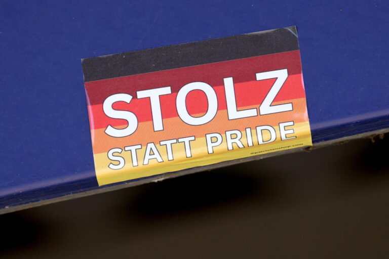Ein rechteckiger Aufkleber mit der Deutschlandflagge im Hintergrund und dem Text „Stolz statt Pride“ klebt auf einer blauen Oberfläche. Der Sticker stammt aus dem Onlineversand „patriotenshop.com“ und wurde auch bei der Aktion gegen die Linkspartei in Hofgeismar eingesetzt. Sticker mit Deutschlandfarben und der Aufschrift „Stolz statt Pride“: Ein Motiv, das auch am Schaukasten der Linken in Hofgeismar verwendet wurde. Nun ermittelt der Staatsschutz. Foto: picture alliance / Rene Traut Fotografie | Rene Traut