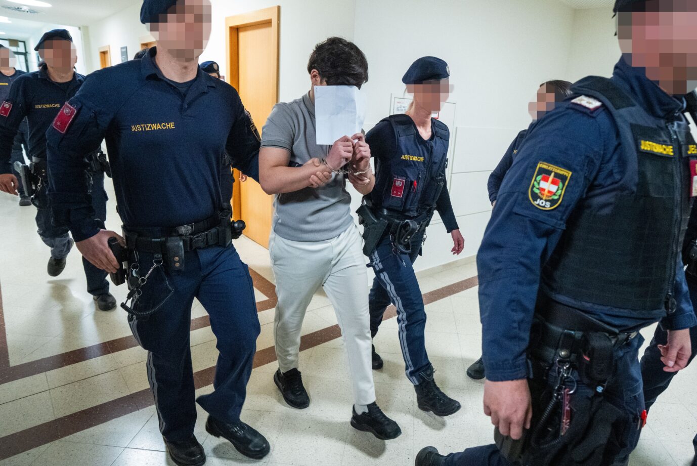 Justizbeamte führen einen der Angeklagten in den Gerichtssaal.