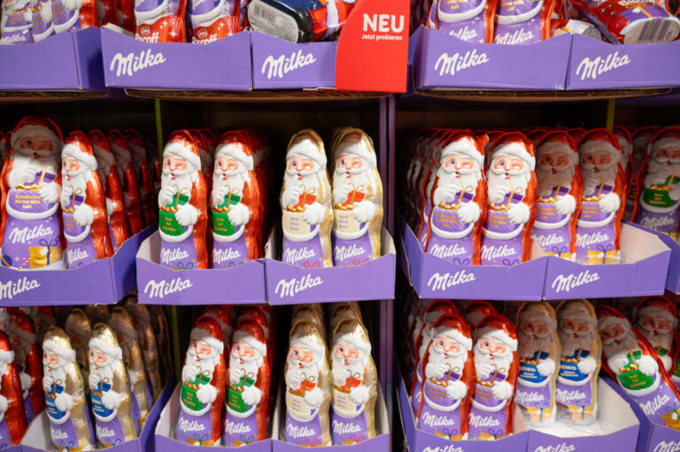 Milka Weihnachtsmänner aus weißer und brauner Schokolade in den Regalen eines Supermarktes, Wintersüßigkeiten mit Nüssen, Trier, Deutschland