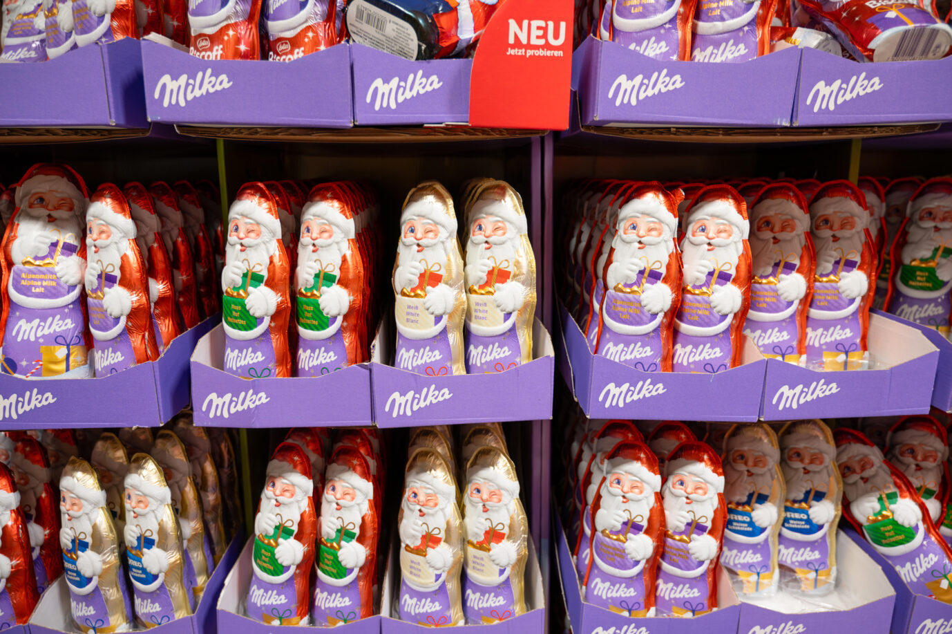 Milka Weihnachtsmänner aus weißer und brauner Schokolade in den Regalen eines Supermarktes, Wintersüßigkeiten mit Nüssen, Trier, Deutschland