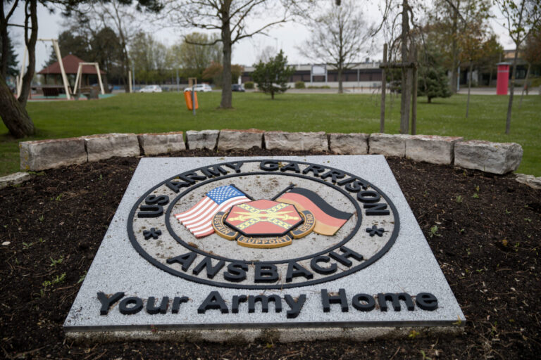 Ein steinernes Schild mit der Aufschrift „US Army Garrison Ansbach“ zeigt US- und Deutschlandflagge. Hintergrund: Die Bundesregierung will notfalls Gehälter ziviler US-Beschäftigter in Deutschland vorfinanzieren, falls Washington nicht zahlt. Eingang zur US-Army-Garnison im mittelfränkischen Ansbach: Auch dort arbeiten zivile Ortskräfte, deren Löhne wegen der Haushaltssperre in den USA gefährdet sind. Foto: picture alliance / Daniel Karmann/dpa | Daniel Karmann
