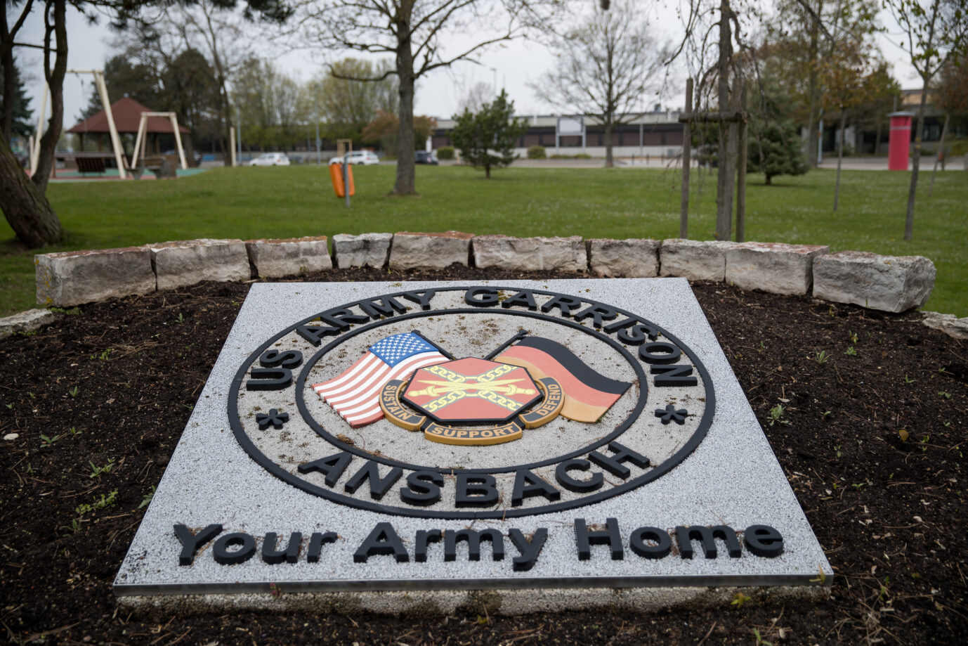 Ein steinernes Schild mit der Aufschrift „US Army Garrison Ansbach“ zeigt US- und Deutschlandflagge. Hintergrund: Die Bundesregierung will notfalls Gehälter ziviler US-Beschäftigter in Deutschland vorfinanzieren, falls Washington nicht zahlt. Eingang zur US-Army-Garnison im mittelfränkischen Ansbach: Auch dort arbeiten zivile Ortskräfte, deren Löhne wegen der Haushaltssperre in den USA gefährdet sind. Foto: picture alliance / Daniel Karmann/dpa | Daniel Karmann