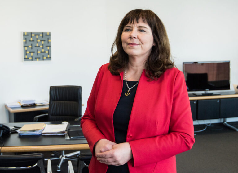 Eine Frau mit dunklen Haaren steht in einem Büro und sortiert Akten auf einem Schreibtisch. Sie trägt ein rotes Jackett. Das Bild zeigt Ludwigshafens Oberbürgermeisterin Jutta Steinruck an ihrem ersten Arbeitstag im Rathaus, 2018. Jutta Steinruck in ihrem Büro: Die Staatsanwaltschaft kennt nach Morddrohungen „nur wenige Verfahren“. Foto: picture alliance / Andreas Arnold/dpa | Andreas Arnold