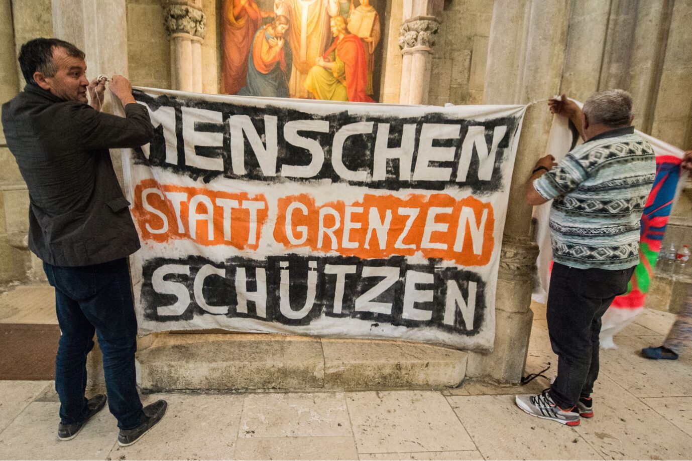 Das Bild zeigt linke Migrations-Unterstützer in einer Kirche. Kirchenasyl ist inzwischen ein politisches Reizthema.
