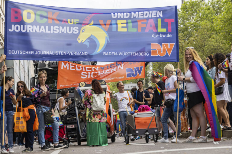 Eine Gruppe von Menschen trägt bunte Transparente und Fahnen mit der Aufschrift „Bock auf Journalismus“ und „Medienvielfalt sichern“. Gezeigt ist der Deutsche Journalisten-Verband bei einer Demonstration in Stuttgart, während der Verband zu den Angriffen auf die Redaktion von Apollo News bislang keine Stellung nahm. Mitglieder des Deutschen Journalisten-Verbandes bei einer Demonstration in Stuttgart: Öffentlich zeigt sich der Verband gern, zu den Aufrufen gegen „Apollo News“ schweigt er bislang. Foto: IMAGO / Arnulf Hettrich