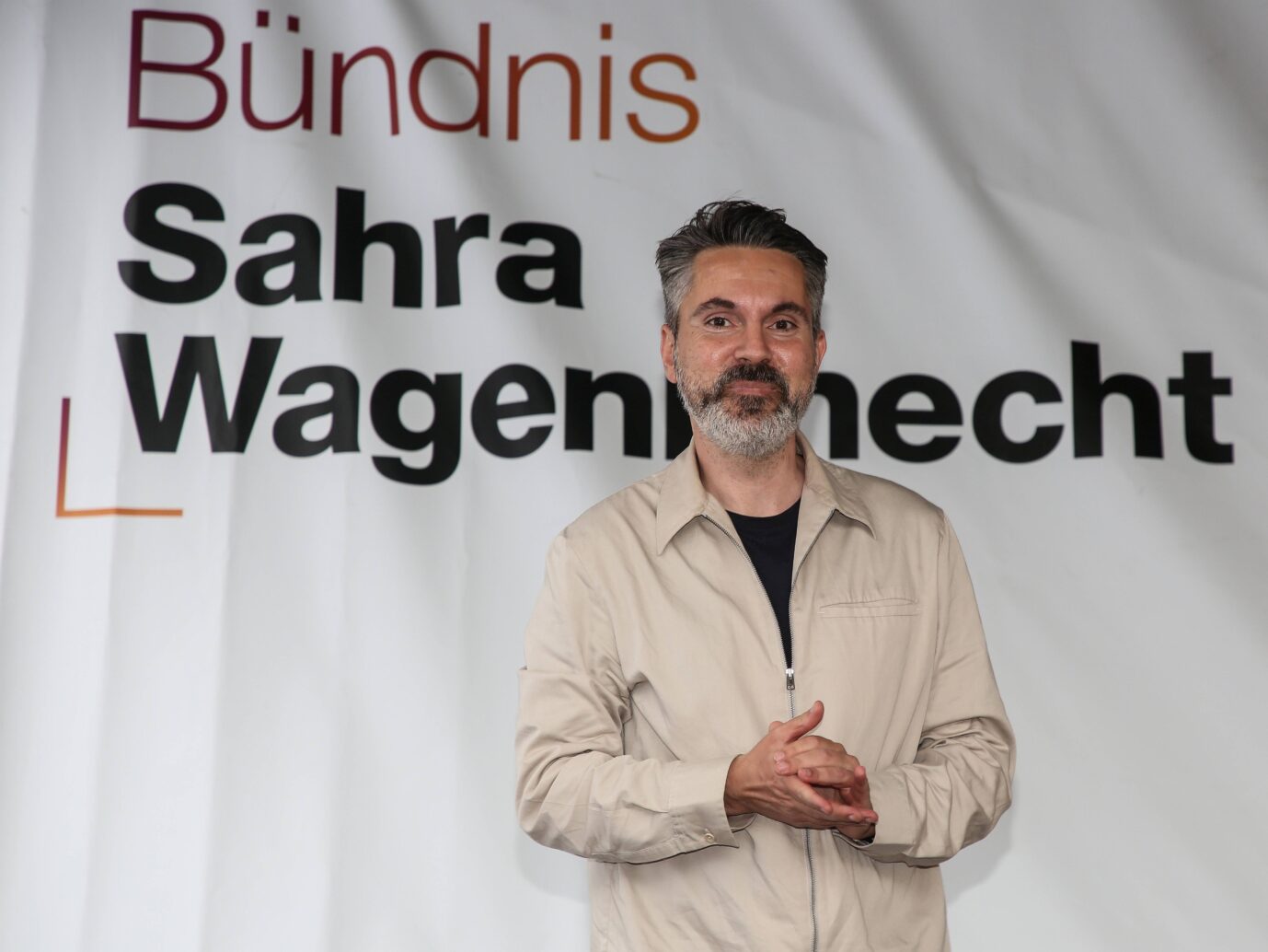 BSW-Politiker Fabio De Masi steht vor einem Banner seiner Partei