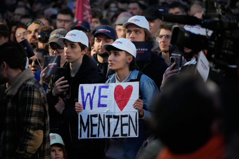 Junge Polen mit weißen Mützen stehen auf einer Straße in Posen und halten ein Schild mit der Aufschrift "We love Mentzen" hoch – sie sind Fans des polnischen rechten Präsidentschaftskandidaten Sławomir Mentzen (Konfederacja) – allgemein rücken junge Europäer nach rechts, was sich in verschiedenen Wahlen zeigt