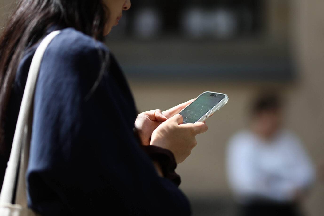 Eine junge Frau tippt auf einem Smartphone herum – bald könnte die EU ihre Chats überwachen