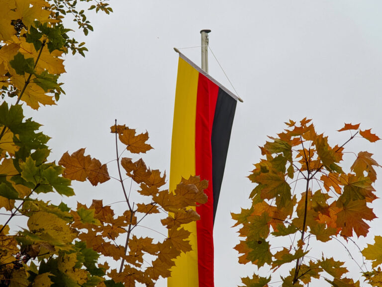 Deutschlandflagge hängt an einem Mast zwischen herbstlichen Baumblättern, aufgenommen in Fulda. Bezug zur Meldung über Ermittlungen nach einer Flaggen-Aktion im Sauerland. Deutschlandflagge an einem Mast in herbstlicher Umgebung: Nach nächtlichen Hissaktionen im Sauerland ermittelt der Staatsschutz. Foto: IMAGO / NurPhoto