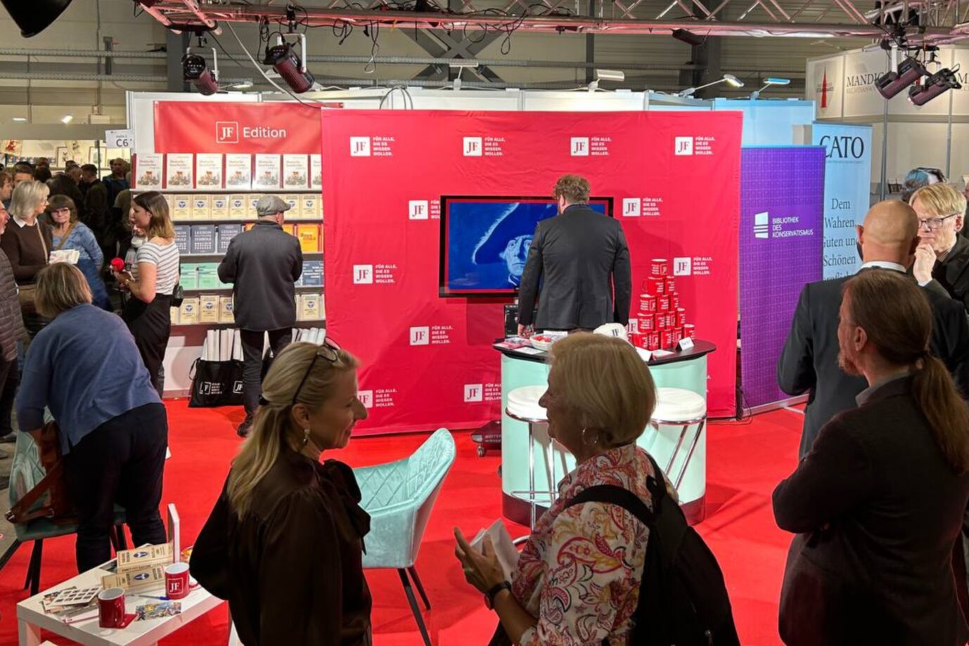 Am Stand der Jungen Freiheit sieht man einen roten Teppich, einen weißen Tisch und ein rotes Banner - es ist Seitenwechsel Buchmesse
