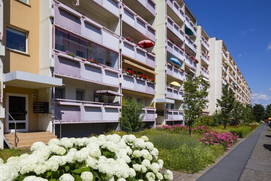 Man sieht Balkone, Fenster und die Eingangstür von Plattenbauten vom Typus des WBS 70 in Dresden-Plauen