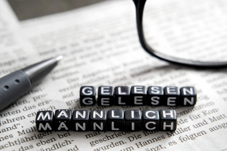 Zwei Reihen schwarzer Würfel ergeben die Wörter „männlich gelesen“ – es handelt sich um ein Symbolbild dafür, daß das Landesgericht Frankfurt einen non-binäre-Person als Mann anreden darf