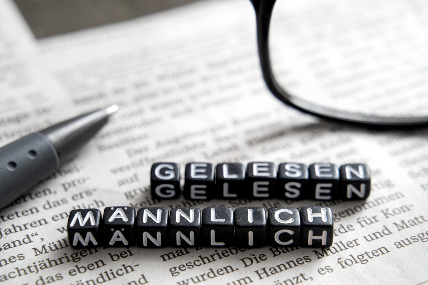 Zwei Reihen schwarzer Würfel ergeben die Wörter „männlich gelesen“ – es handelt sich um ein Symbolbild dafür, daß das Landesgericht Frankfurt einen non-binäre-Person als Mann anreden darf