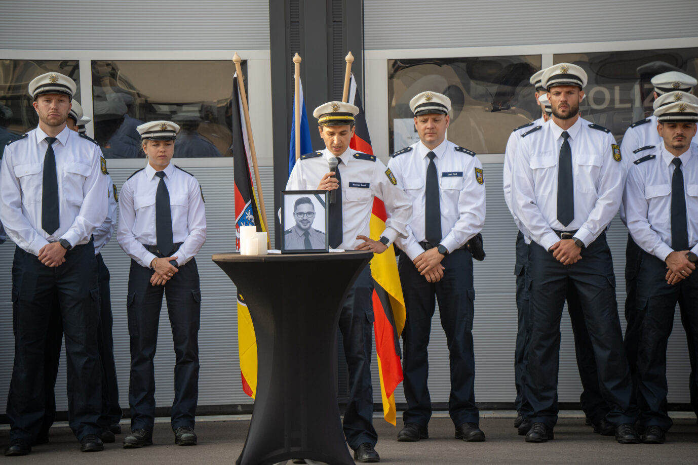 Polizisten stehen bei einer Schweigeminute für den in Völklingen getöteten Polizeioberkommissar Simon B. an dessen Porträtfoto. Bundesweite Schweigeminuten sollen an den im Dienst erschossenen Beamten erinnern.