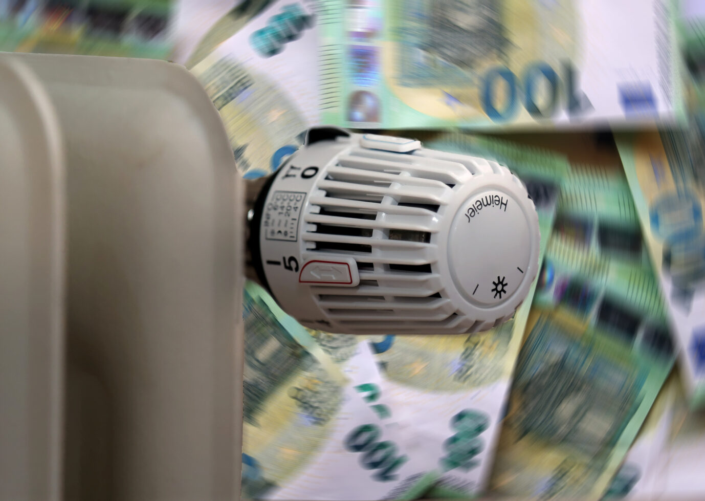 Eine Heizung mit Geldscheinen im Hintergrund. Eine Gaskrise treibt die Preise hoch.