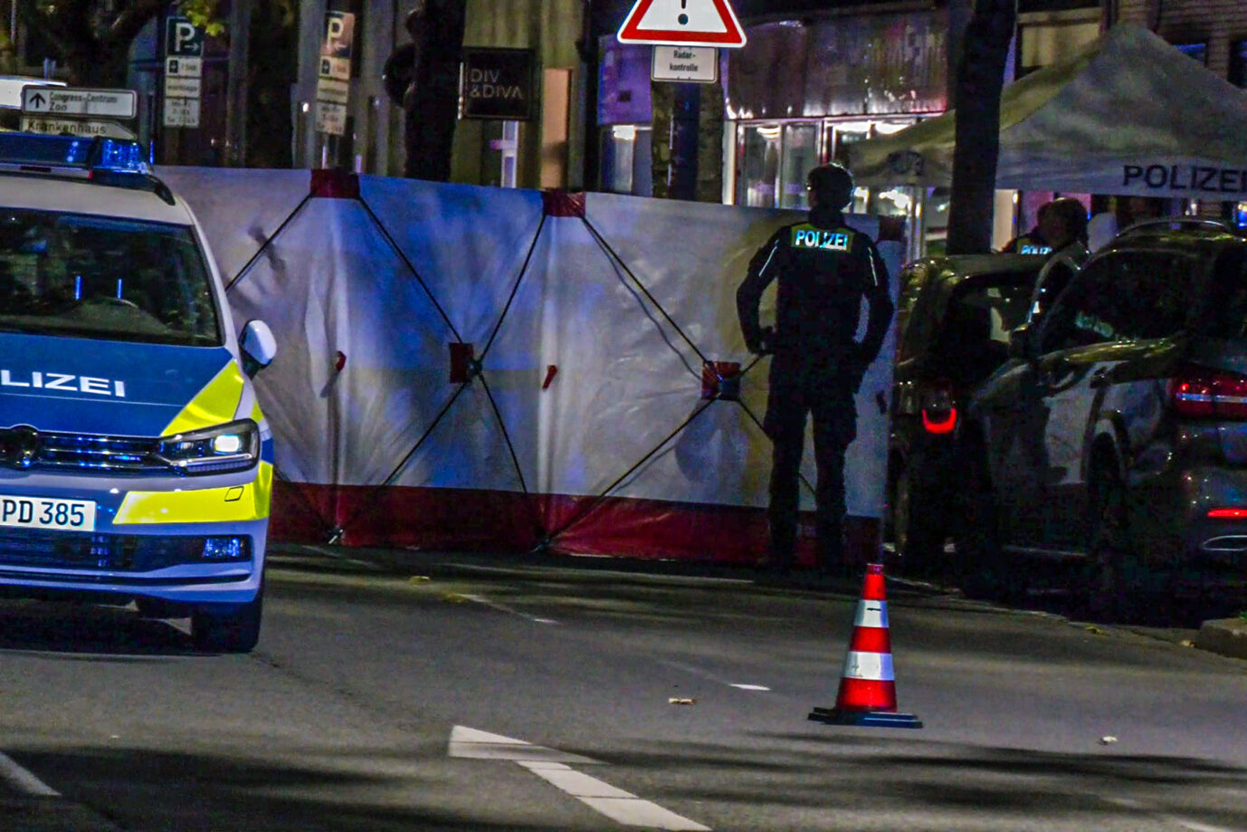 Beamte der Polizei stehen an einem Tatort. Am Abend sind im Stadtteil Vahrenwald Schüsse gefallen. Eine Person ist ums Leben gekommen, wie die Polizei auf der Social-Media-Plattform X schreibt. Rettungskräfte haben Verletzte versorgt und sie in umliegende Krankenhäuser gebracht. Ein Polizeihubschrauber war im Einsatz. Ausländer sind überproportional kriminell. Die Vahrenwalder Straße war zwischen Niedersachsenring und der Straße "Großer Kolonnenweg" in beide Richtungen gesperrt.